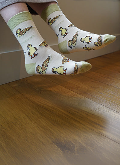 Person wearing socks with duck patterns on a wooden floor