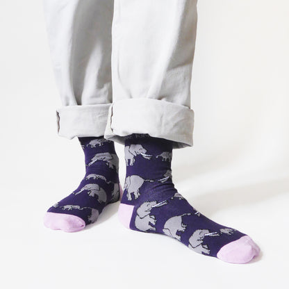 standing model wearing purple and pink elephant bamboo socks; the left foot is forward and angled to the side