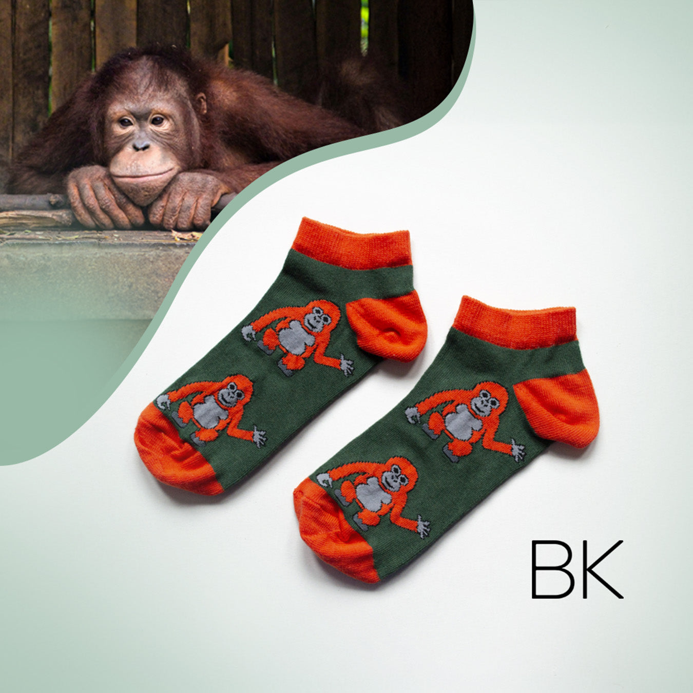 flat lay of dark green and red ankle trainer socks featuring orangutan design with orangutan imagery