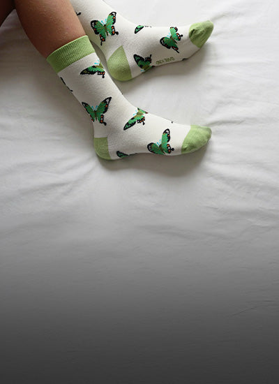 White socks with green butterfly patterns on a white surface