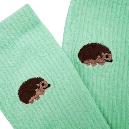 Close up to minimalist flat lay picture of pastel green ribbed socks with hedgehog motif design