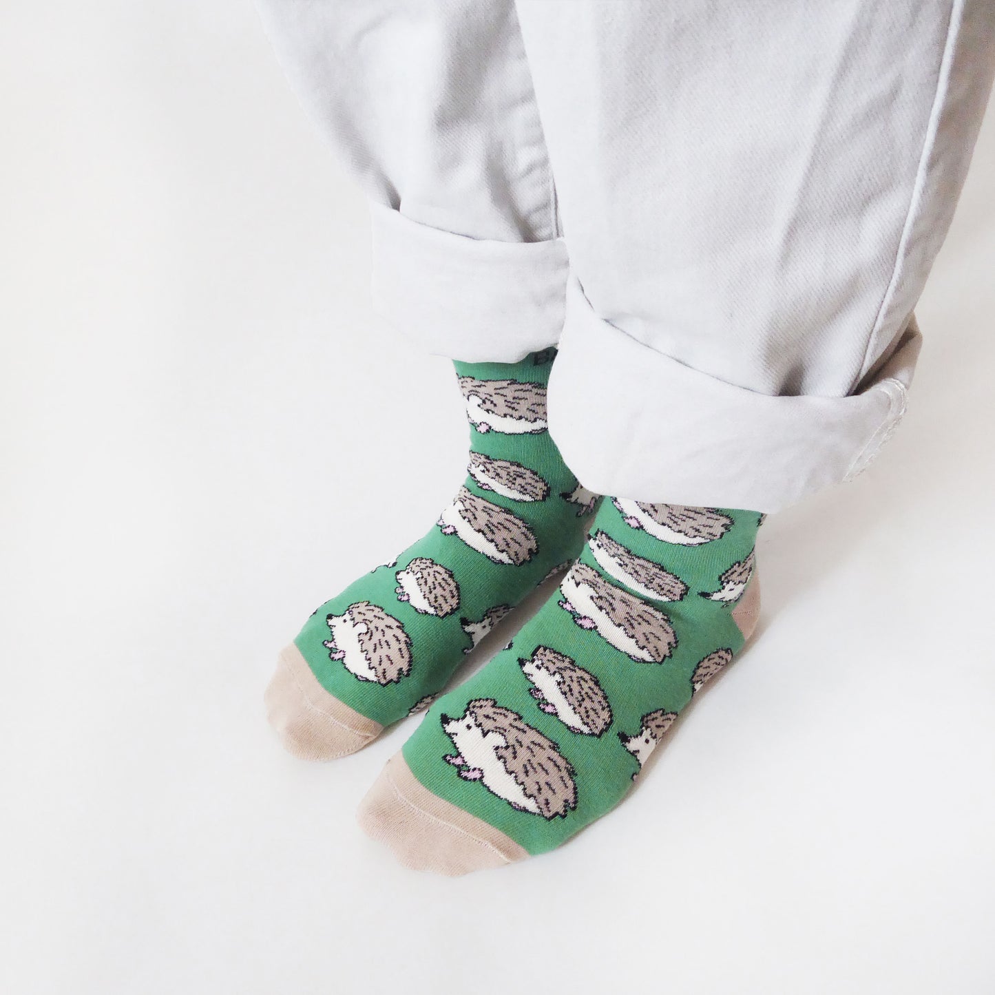 side angle view of standing model wearing green bamboo hedgehog socks