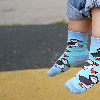 Children's feet wearing socks with puffin design on a pavement background