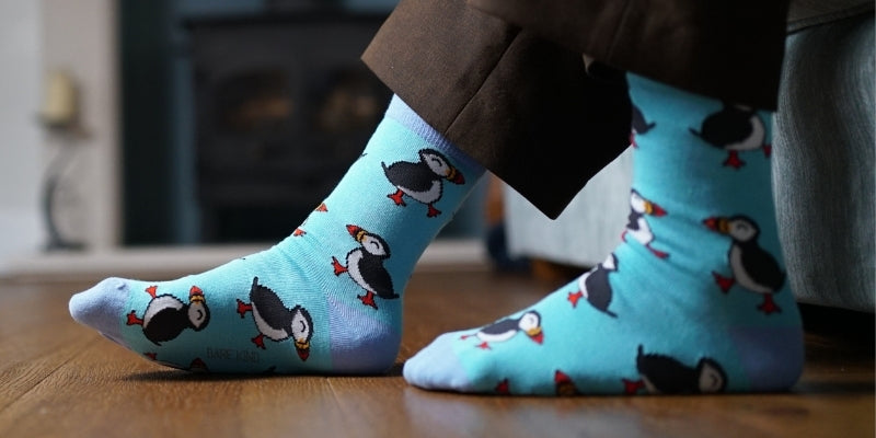 Blue socks with penguin design worn by a person indoors.