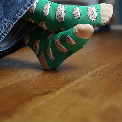 Green socks with hedgehog pattern worn on a wooden floor