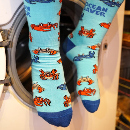 model sitting on washing machine and wearing blue ocean saver crab bamboo socks 