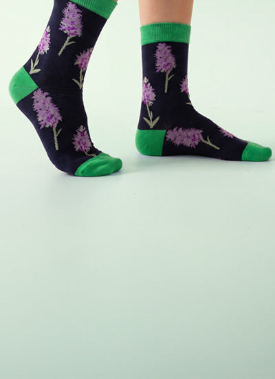 Floral-patterned socks with green accents on a light gray background