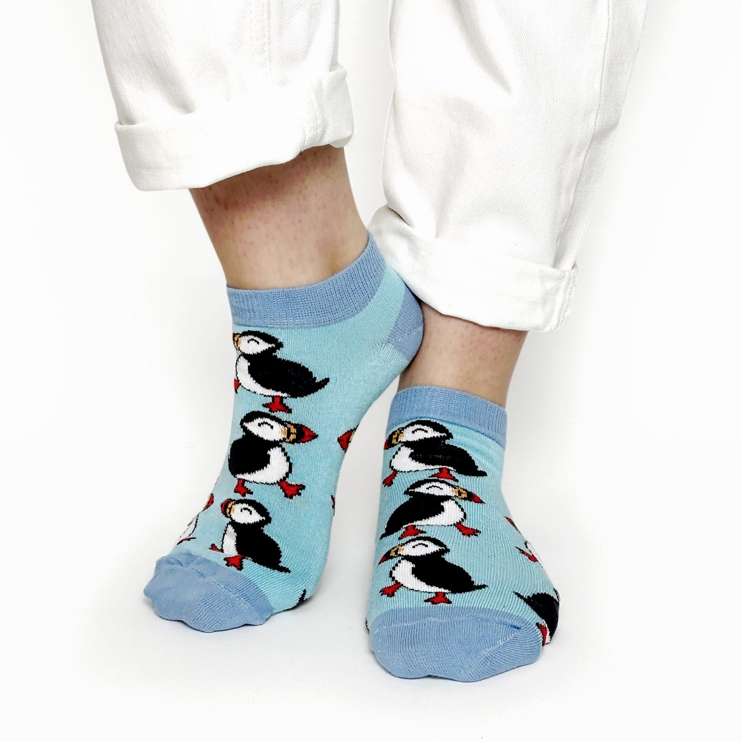 model wearing blue puffin trainer socks and white troursers