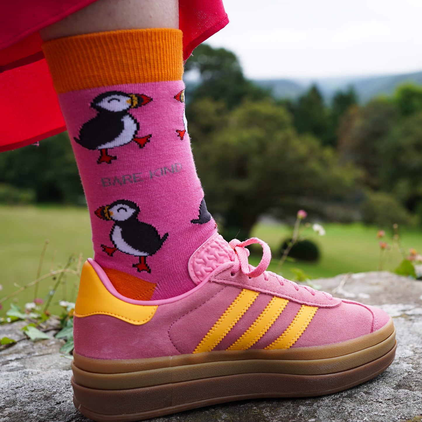 lifestyle image of model wearing pink puffin socks with pink and yellow shoes