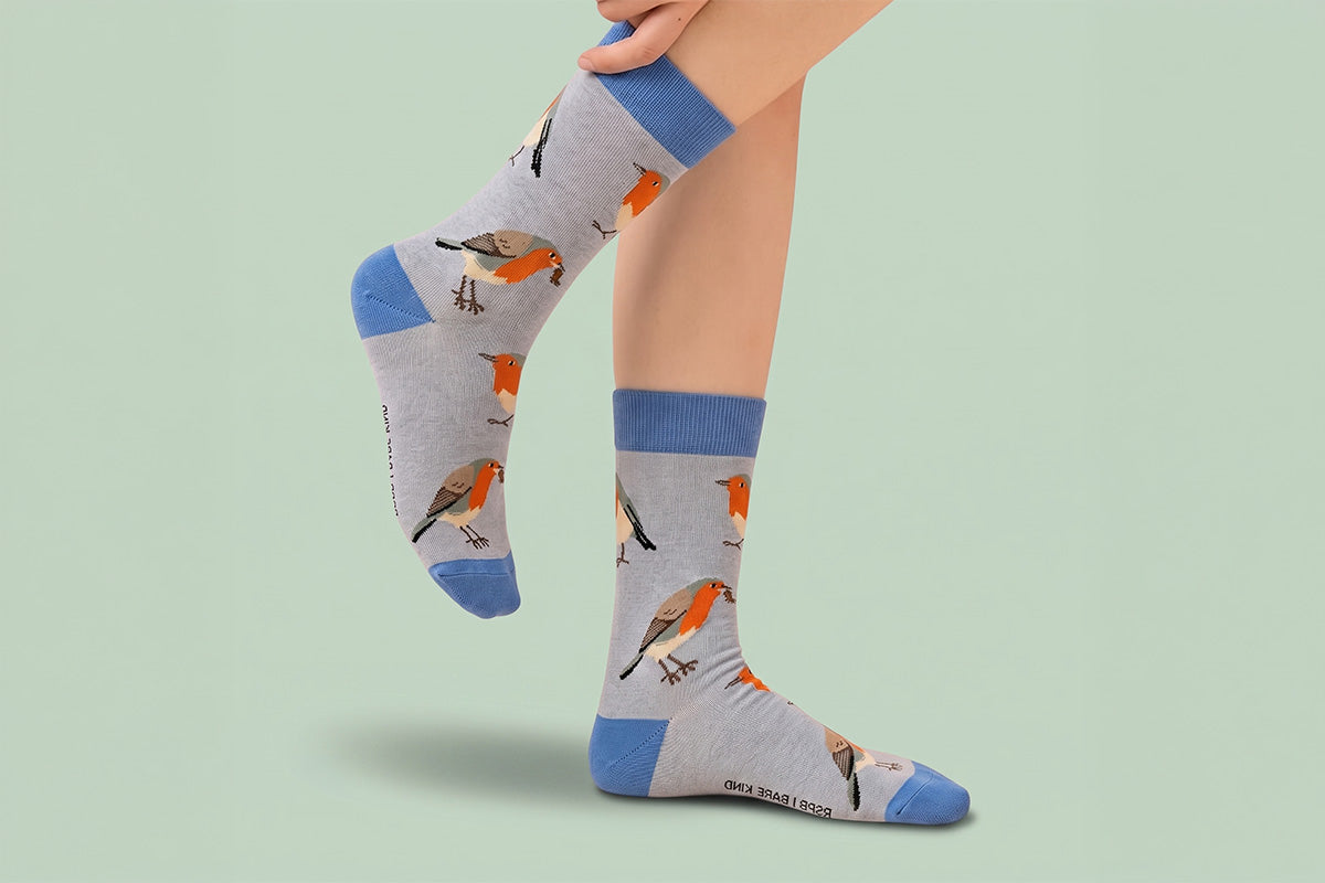 Gray socks with bird pattern worn by a person on a light green background