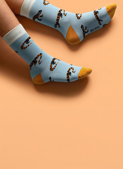 Light blue socks with salamander pattern and orange toes on a peach background