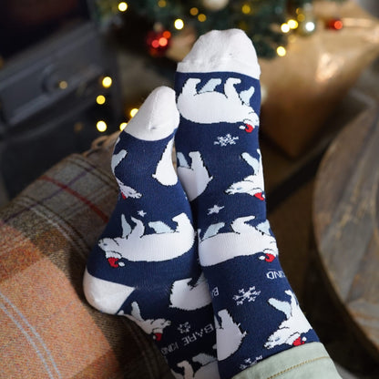 lifestyle image of model wearing blue polar bear christmas bamboo socks lying on a sofa