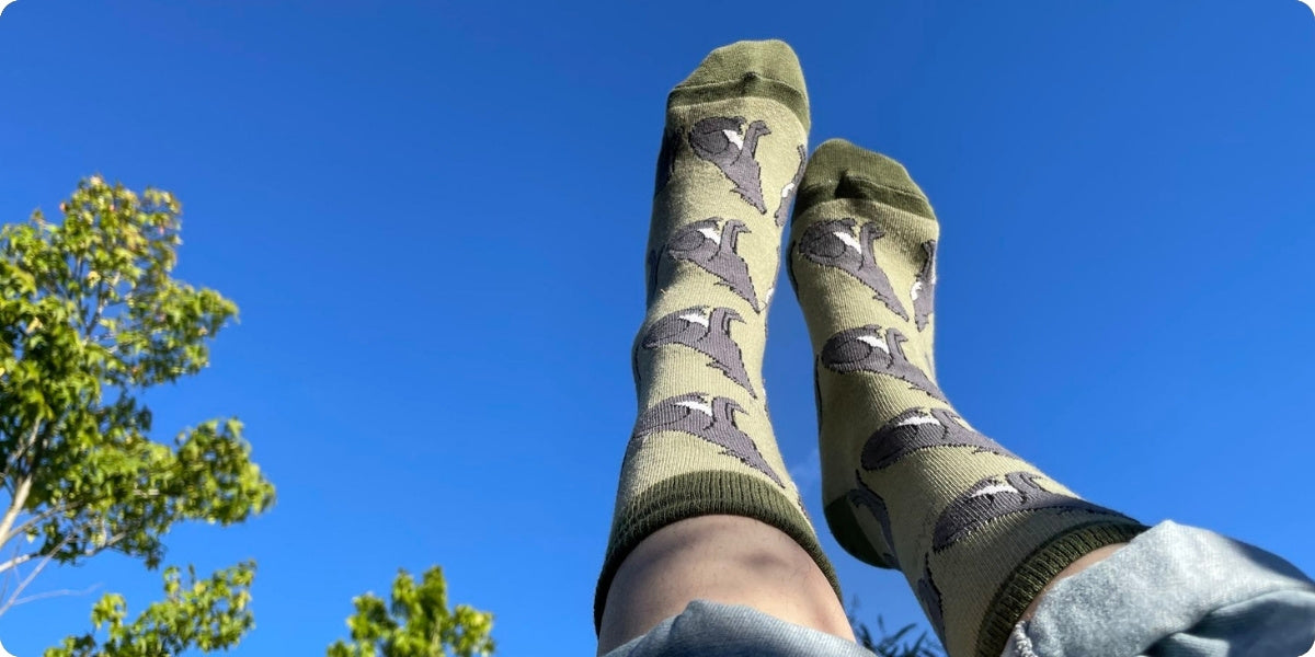Green wolves bamboo socks worn by a person against a blue sky and tree background