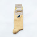 minimalist folded flat lay of pastel yellow ribbed bamboo socks with embroidered gorilla motif on the cuff. wrapped in 100% recyclable cardboard packaging