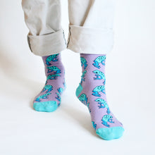 front view of standing model wearing lilac and blue frog bamboo socks with the left foot forward and heel up