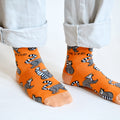 closeup of orange lemur socks on standing model 