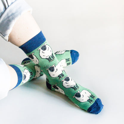 sitting model with ankles crossed wearing green sheep socks