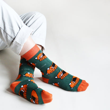 sitting model with crossed ankles wears red panda socks