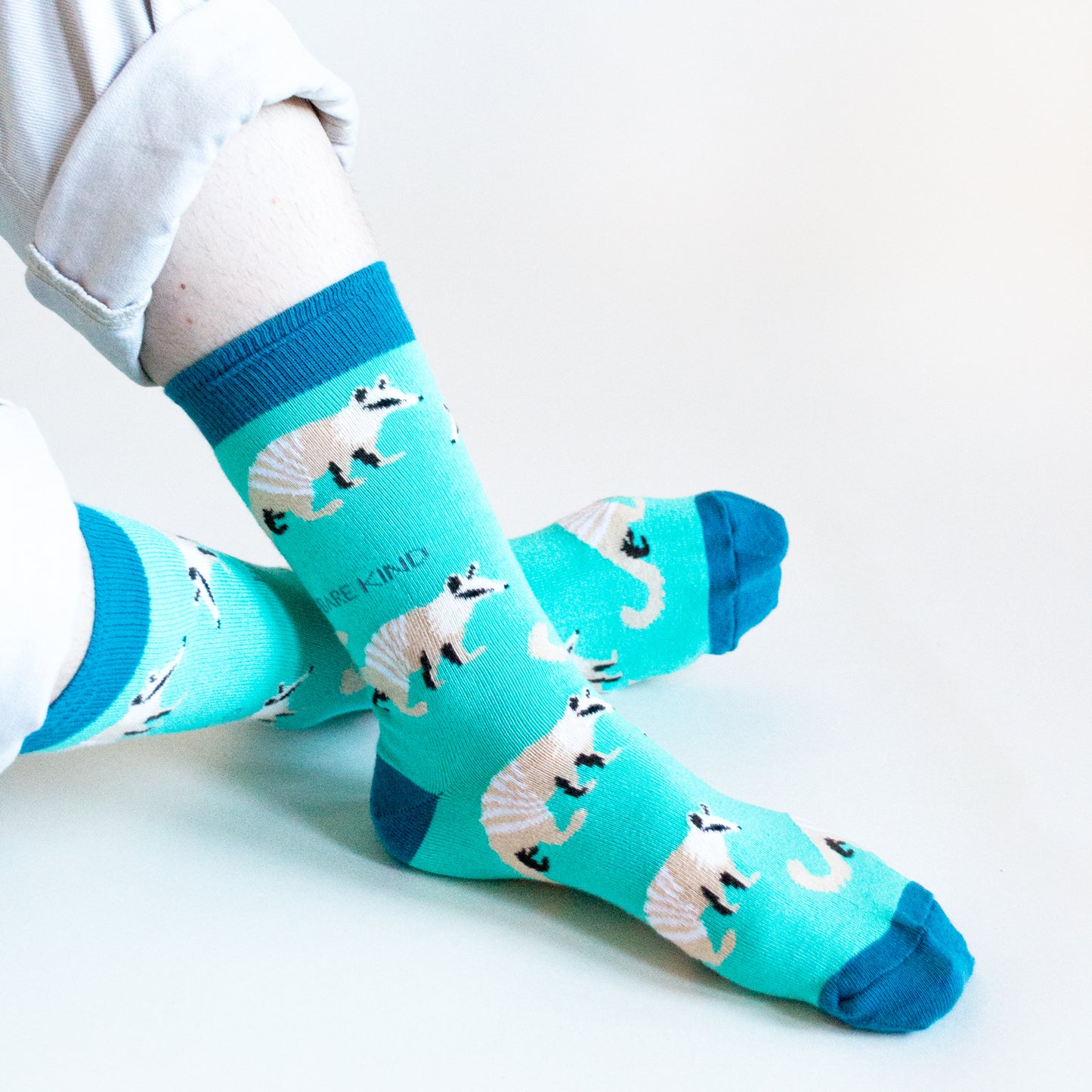 sitting model wearing bright blue numbat socks as the ankles are crossed