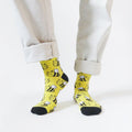 model stands wearing black and yellow bee socks with the right heel lifted, front view