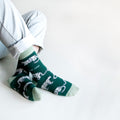 sitting model with ankles crossed wearing green snow leopard bamboo socks