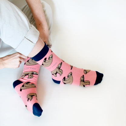 birds eye view of sitting model wearing pink bamboo sloth socks with ankles crossed