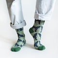 standing model wearing green wolf socks, left heel up